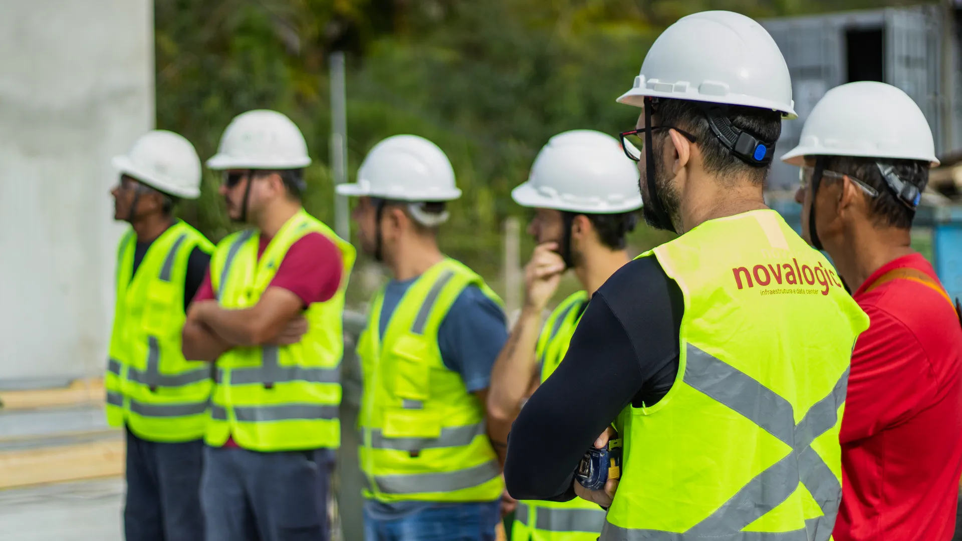 Equipe da Novalogic de capacete e colete refletivo durante briefing de segurança em canteiro de obra