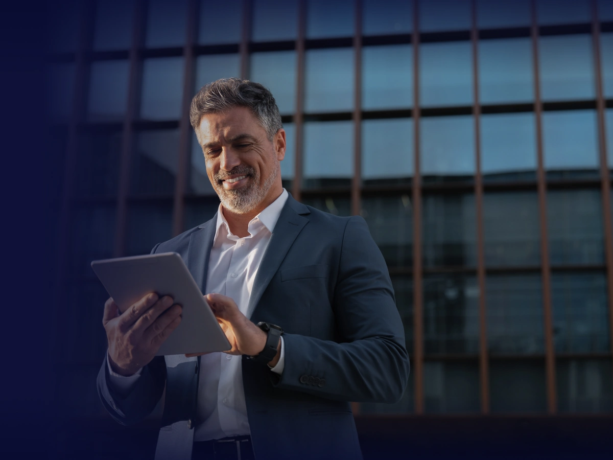 Executivo usando um tablet em frente a um prédio corporativo à noite