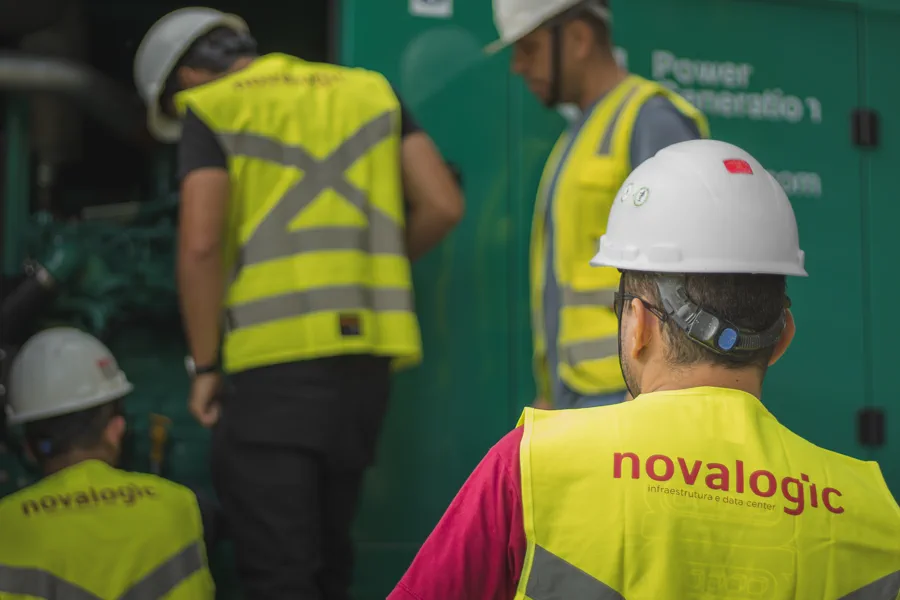 Equipe da Novalogic diante de um grupo gerador em sala técnica