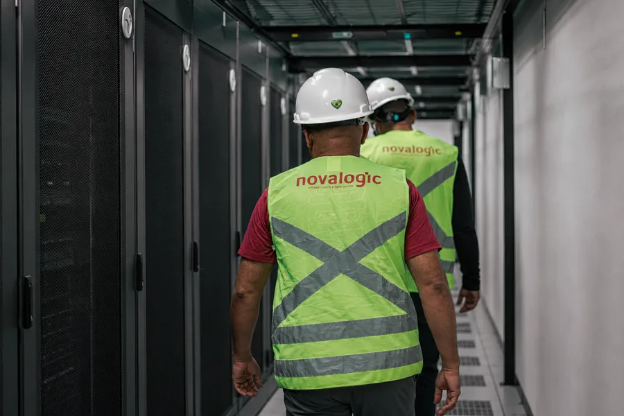 Dois técnicos da Novalogic percorrendo o corredor de um data center